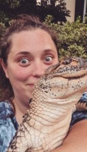 Woman holding a small alligator close to her face.