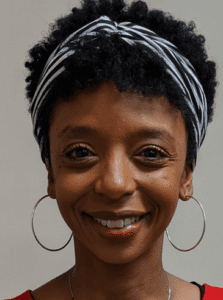 Smiling woman with a striped headband and hoop earrings.