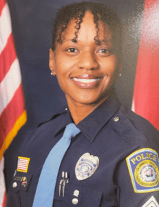 A smiling female police officer in uniform poses for a portrait.