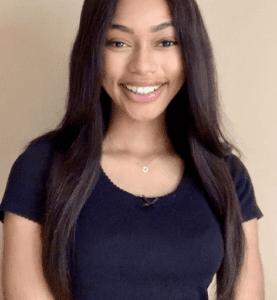 Smiling young woman with long dark hair wearing a black top.