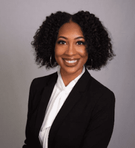 Professional woman in black blazer and white shirt smiling.
